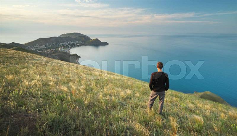 Man on the edge. Cliff of mountain and sea. Conceptual scene, stock photo