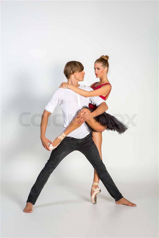 Beautiful ballet couple. ballerina in black tutu skirt. man in jeans and white shirt. studio shot. copy space, stock photo