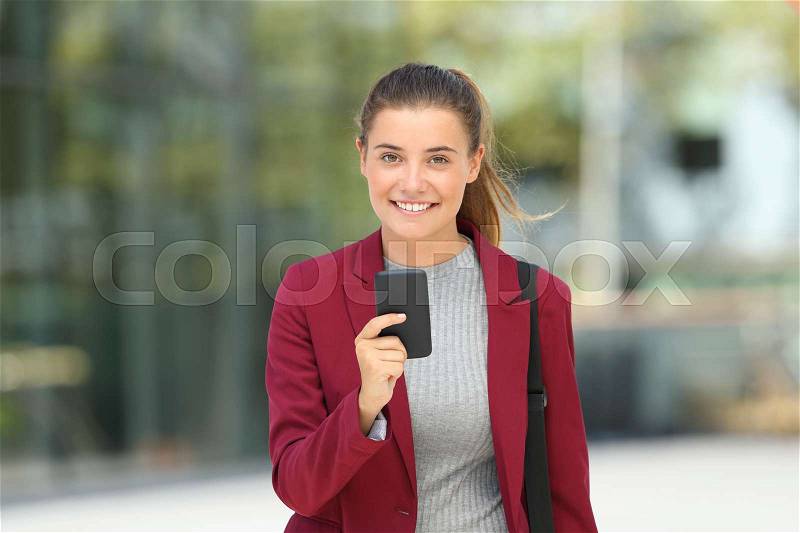 Front view portrait of a young executive holding a mobile phone and looking at you, stock photo