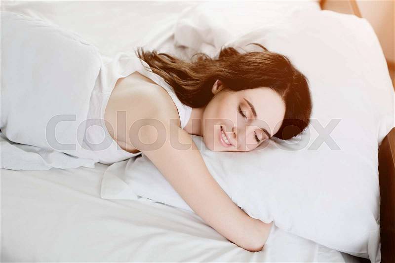 Beautiful young caucasian girl sleeping on bed. Light lifestyle interior in bedroom, stock photo