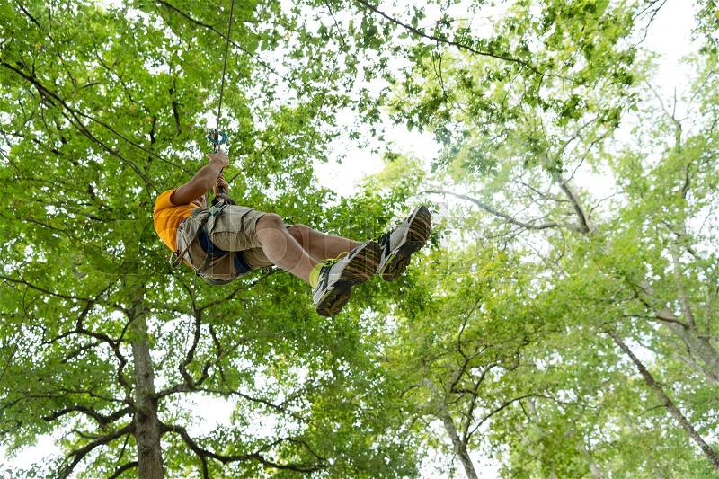 Young woman zip-lining during tree top adventure, stock photo