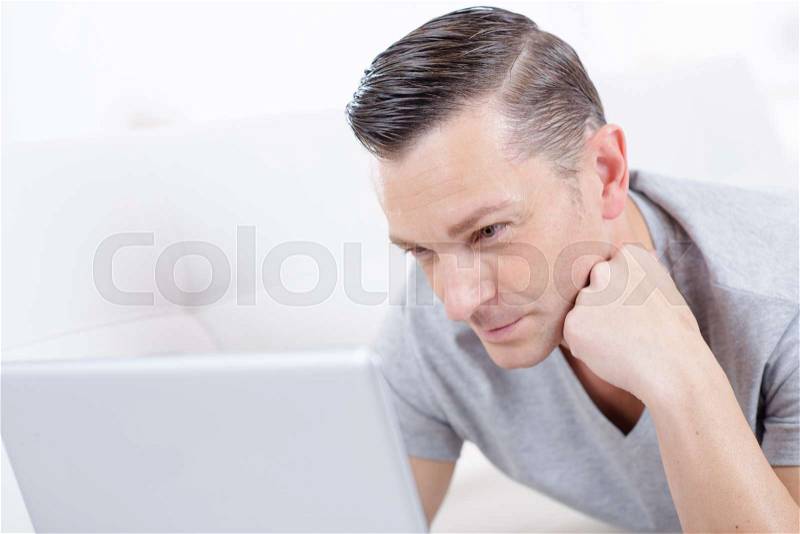 Man with laptop surfing the web at home, stock photo