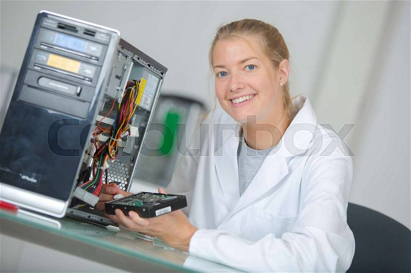 Young smiling woman technician repairs a computer, stock photo