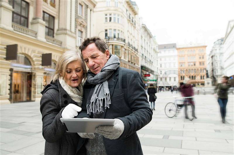 Beautiful senior couple with tablet on a walk in historical centre of the city of Vienna, Austria. Winter, stock photo