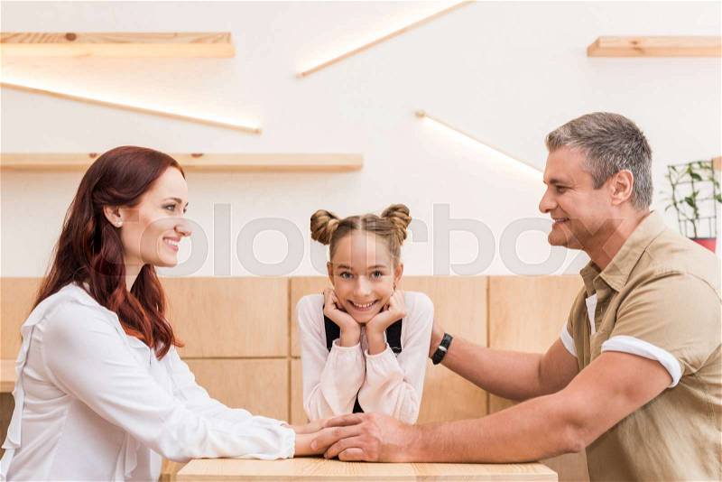 Mature couple with teen daughter sitting in cafe, stock photo