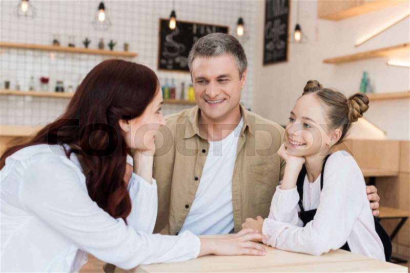 Lovely family embracing in cafe and looking at each other, stock photo