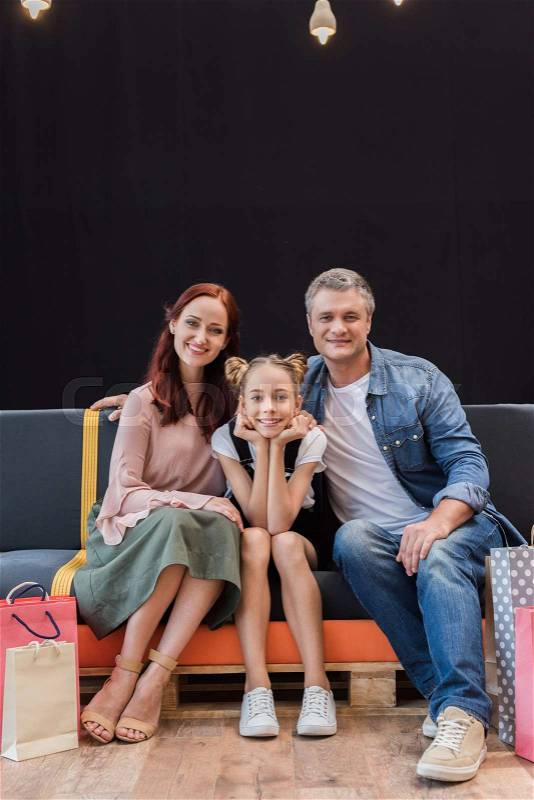Beautiful family sitting on couch with shopping bags, stock photo