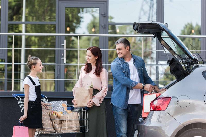 Beautiful happy family packing shopping bags in car, stock photo