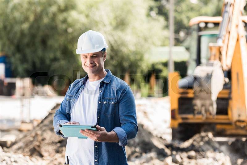Handsome mature construction worker with tablet, stock photo