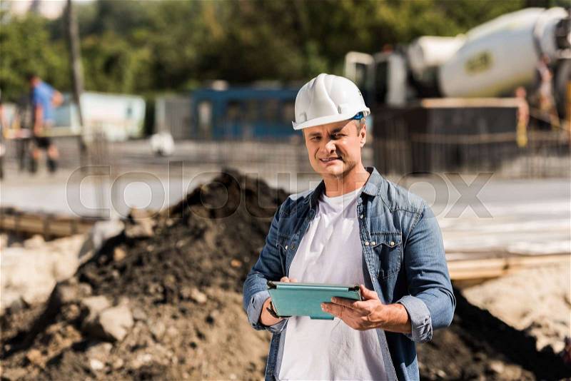 Handsome mature construction worker with tablet, stock photo