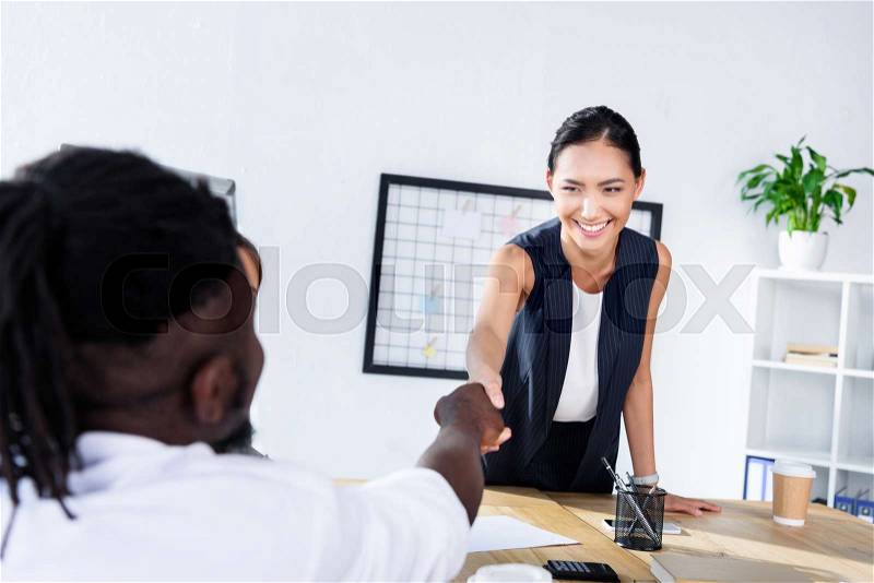 Multicultural business people shaking hands during business meeting in office, stock photo