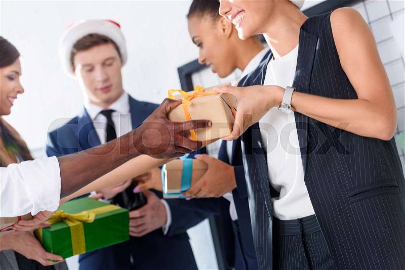 Happy young multiethnic business people with gifts in office, stock photo