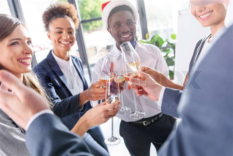 Happy young multiethnic business colleagues drinking champagne in office , stock photo