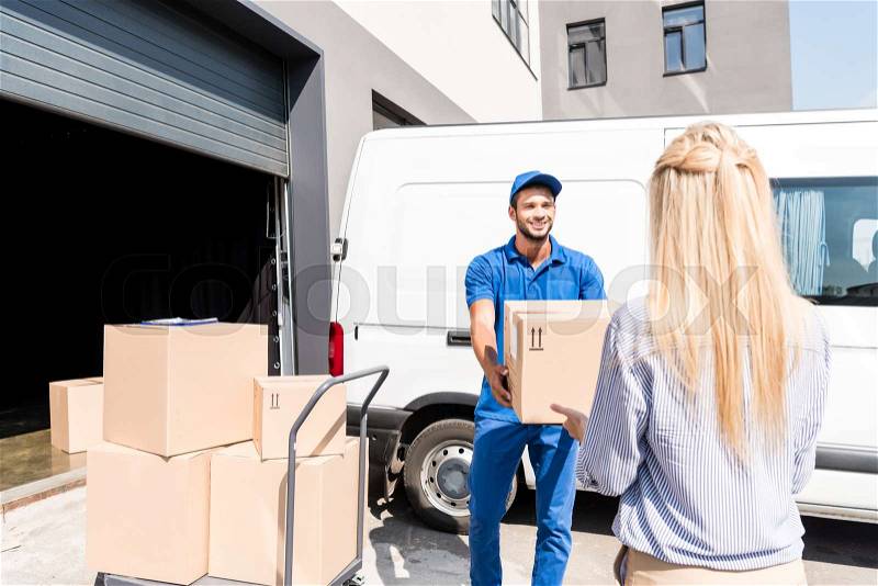 Handsome young courier giving package to woman, stock photo