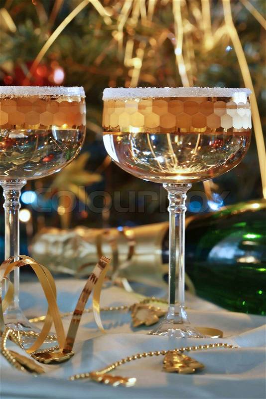Fluted champagne glasses and ribbons on gold background, stock photo