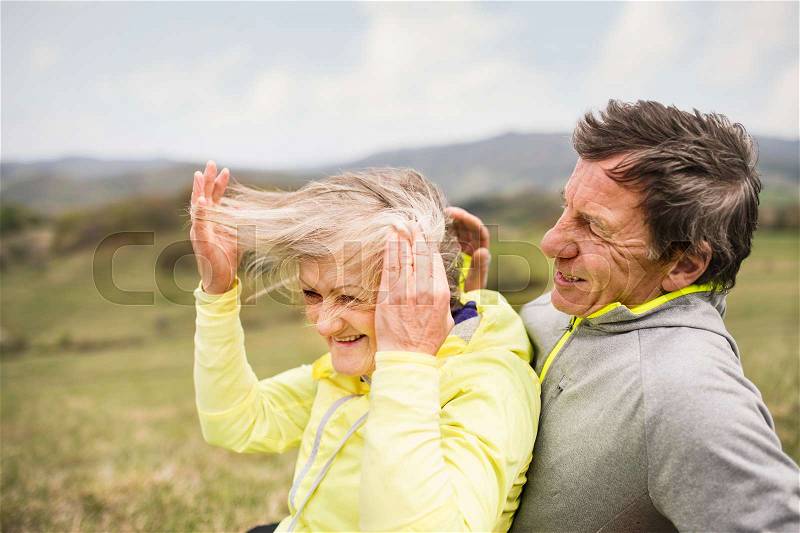Beautiful active senior runners resting outside in sunny autumn nature, hugging, stock photo