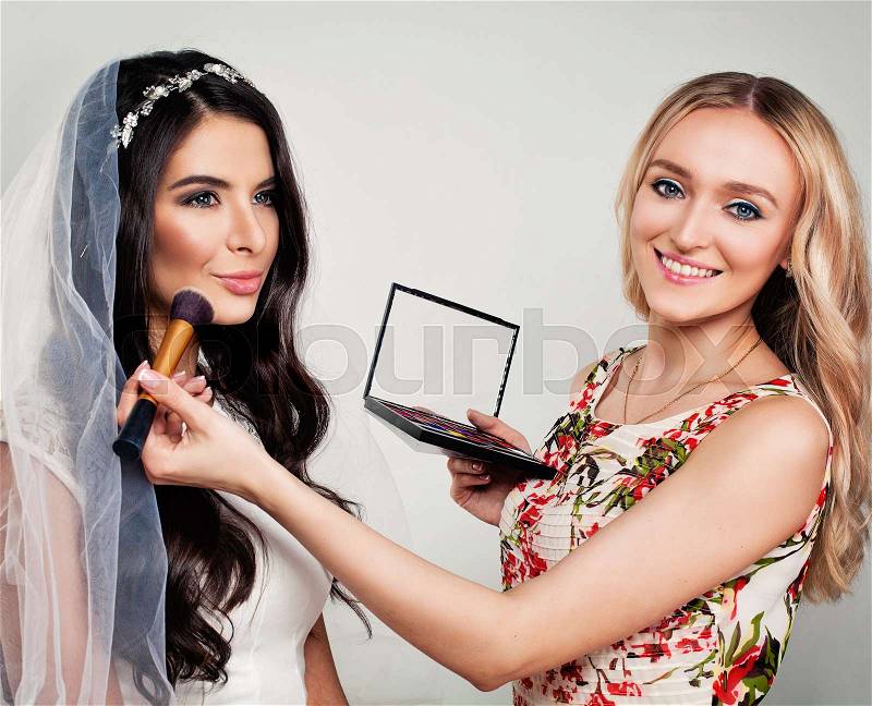 Nice Fashion Model Bride and Woman Makeup Artist with Makeup Brushes, stock photo