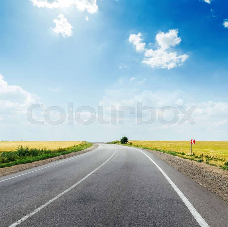 Asphalt road in field and deep blue sky with clouds and sun, stock photo