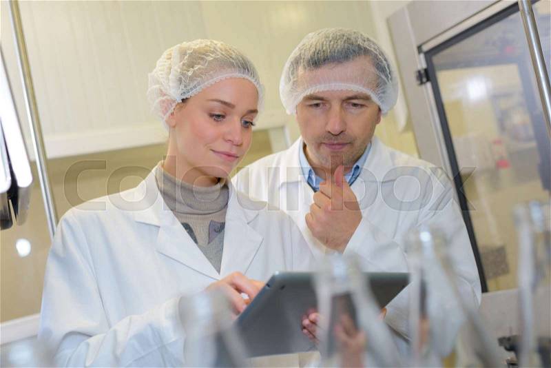 Two workers at production line in high tech plant, stock photo