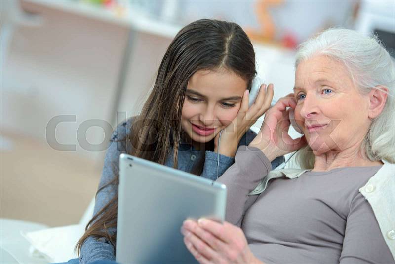 Girl and her beautiful grandma are using a digital tablet, stock photo