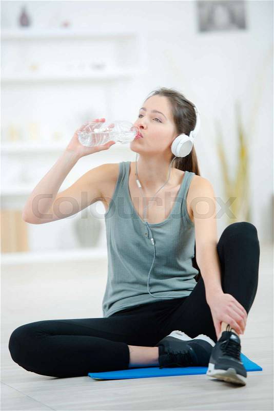 Beautiful girl make yoga execises on floor and drink water, stock photo