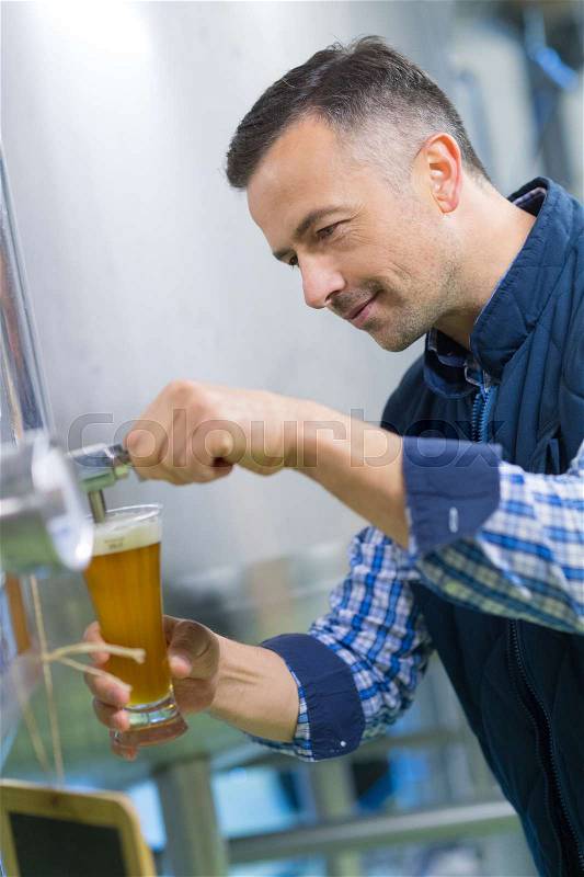 Brewer testing beer at brewery, stock photo
