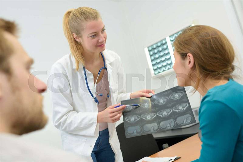 Happy female doctor reading xray results to couple, stock photo
