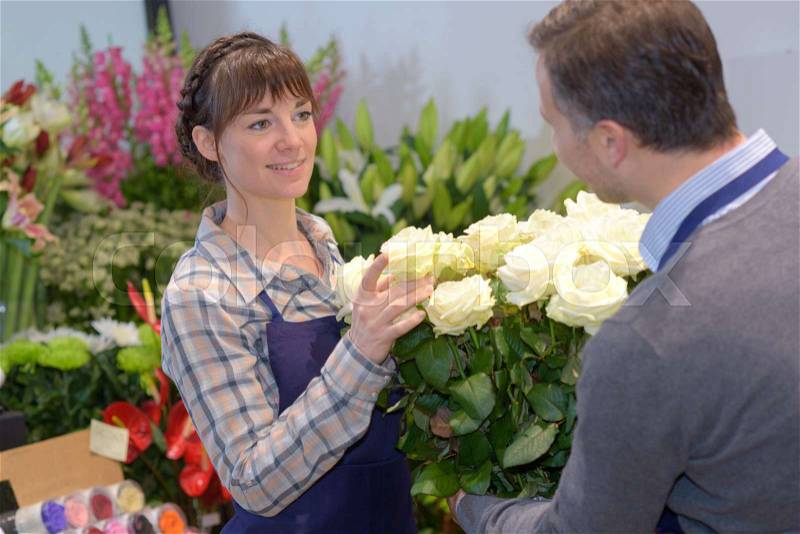 Florist and male customer smelling flower bouquet at store, stock photo