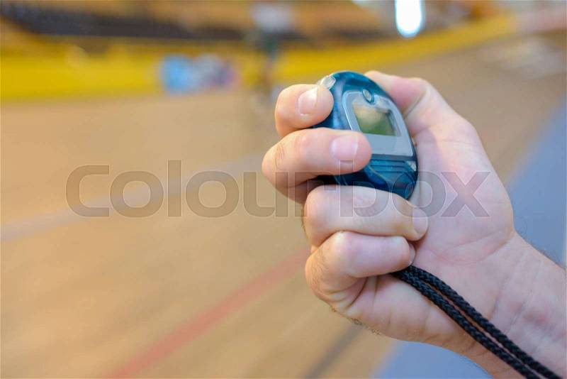 Woman in gym on bike holding stopwatch, stock photo