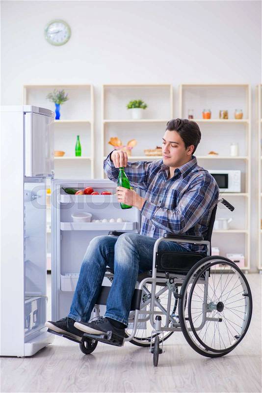 Young disabled injured man opening the fridge door , stock photo