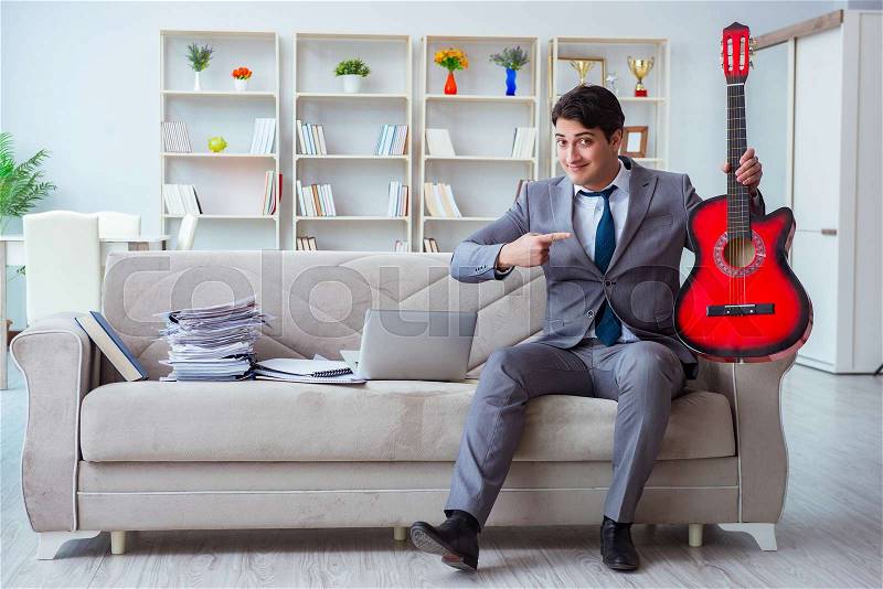 Businessman playing guitar at home, stock photo
