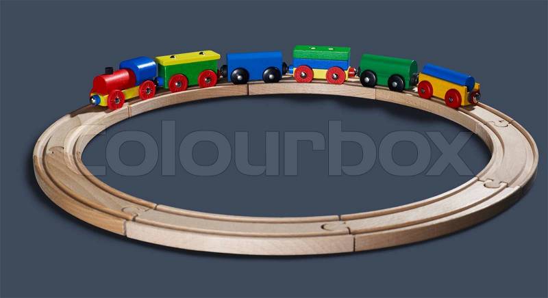 Studio photography of a colorful wooden toy train on a track circle in dark back, stock photo