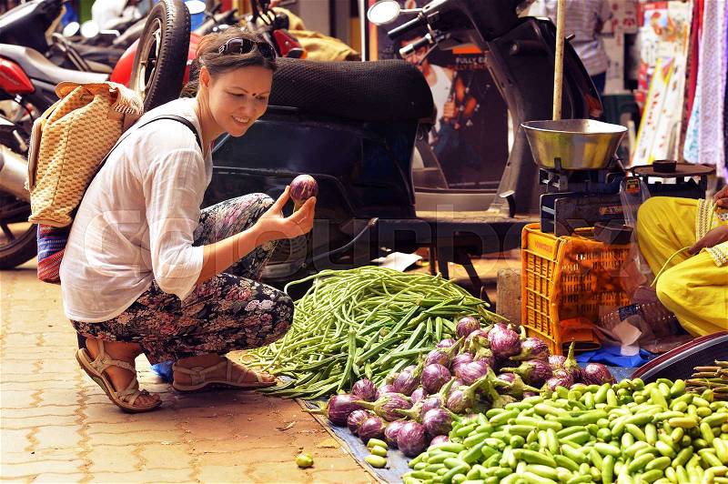 Young woman choosing fresh vegetables on local market, stock photo