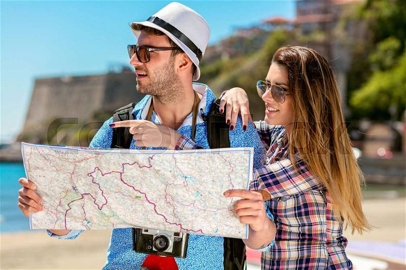 Multiethnic traveler couple using generic local map together on sunny day, stock photo