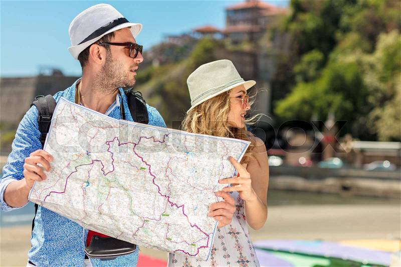 Multiethnic traveler couple using generic local map together on sunny day, stock photo