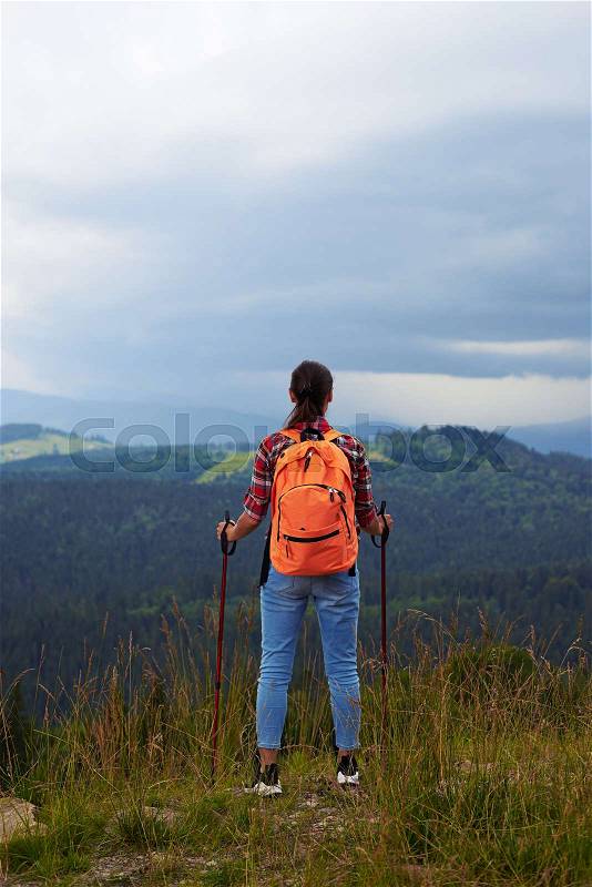 Rear view of woman with hiking poles standing on the edge of the mountain in Carpathian , stock photo