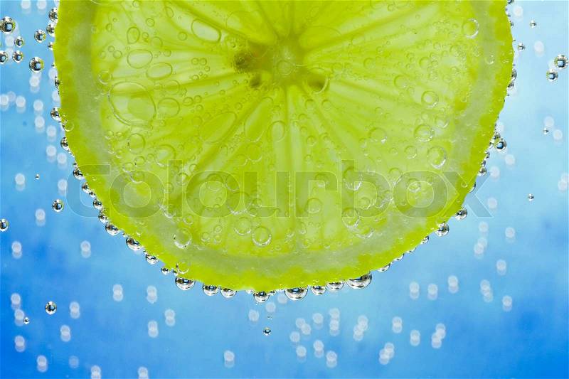 Slice of lime in the water with bubbles, stock photo