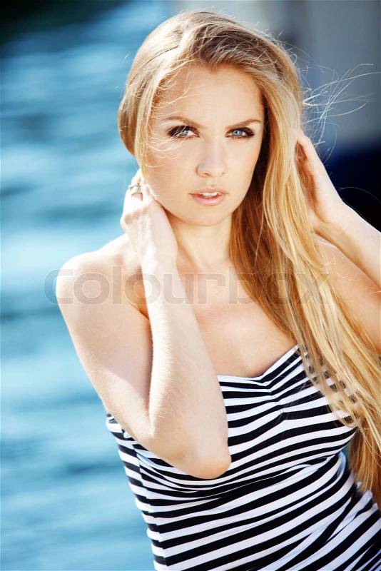 Beautiful sexy woman wearing sailor striped dress posing at beach, stock photo