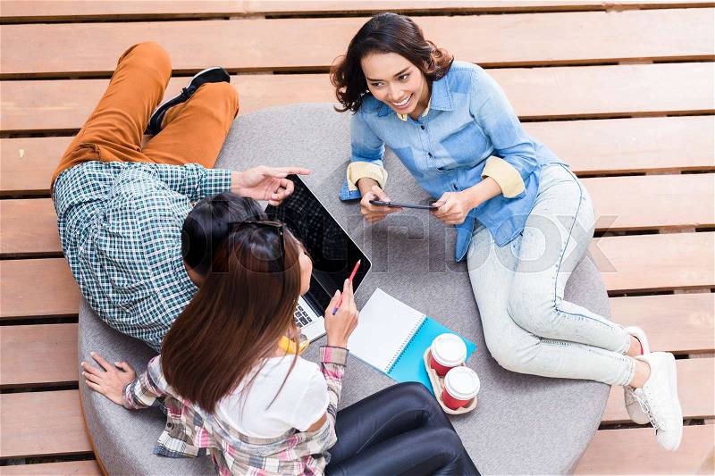 High angle view of three creative employees sharing ideas during brainstorming session in a relaxed working environment, stock photo