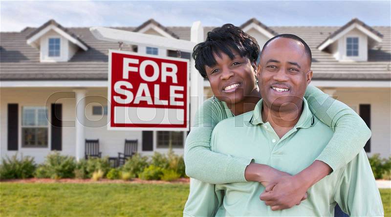 Happy African American Couple In Front of Beautiful House and For Sale Real Estate Sign, stock photo