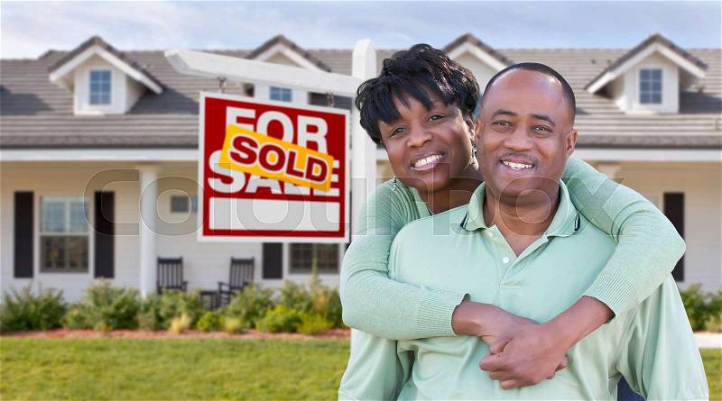 Happy African American Couple In Front of Beautiful House and Sold For Sale Real Estate Sign, stock photo