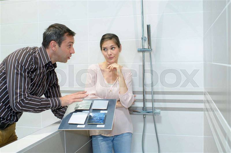 Happy couple of adults choosing ceramic tile for bathroom, stock photo