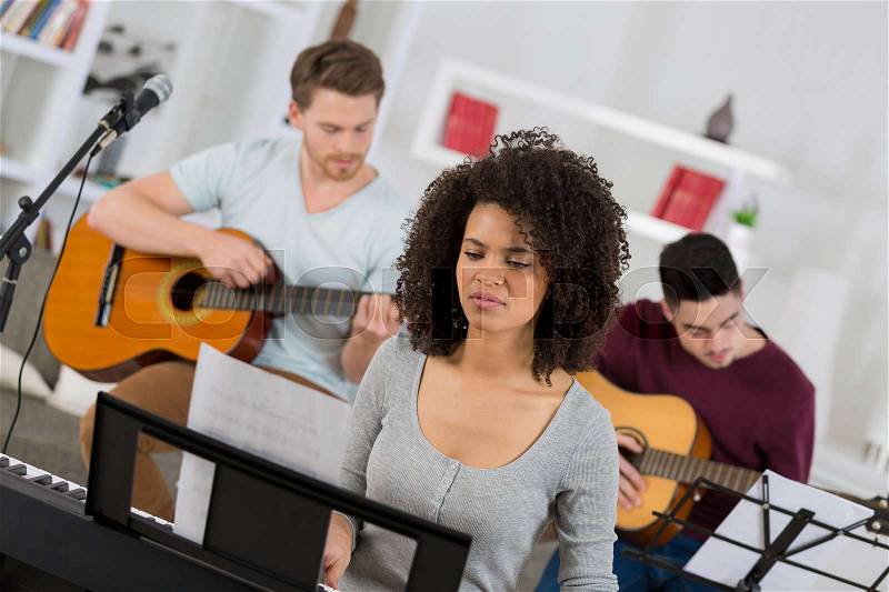 Woman learning a music instrument with friends, stock photo