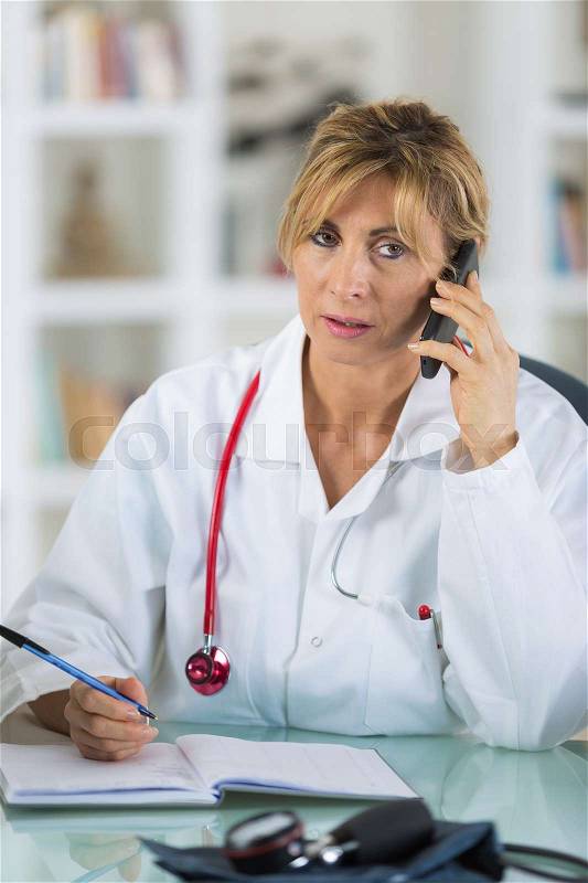 Female doctor talking on phone in diagnostic center, stock photo