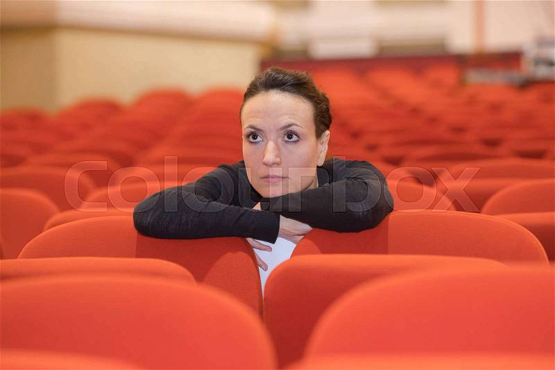 Woman watching movie alone in empty theater auditorium, stock photo