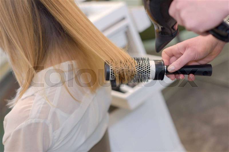 Hairdresser with brush behind young female, stock photo