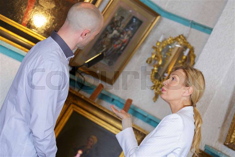 Artist with buyer the picture in art gallery, stock photo
