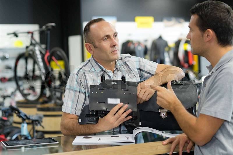 Man asking seller for help in sport bike shop, stock photo