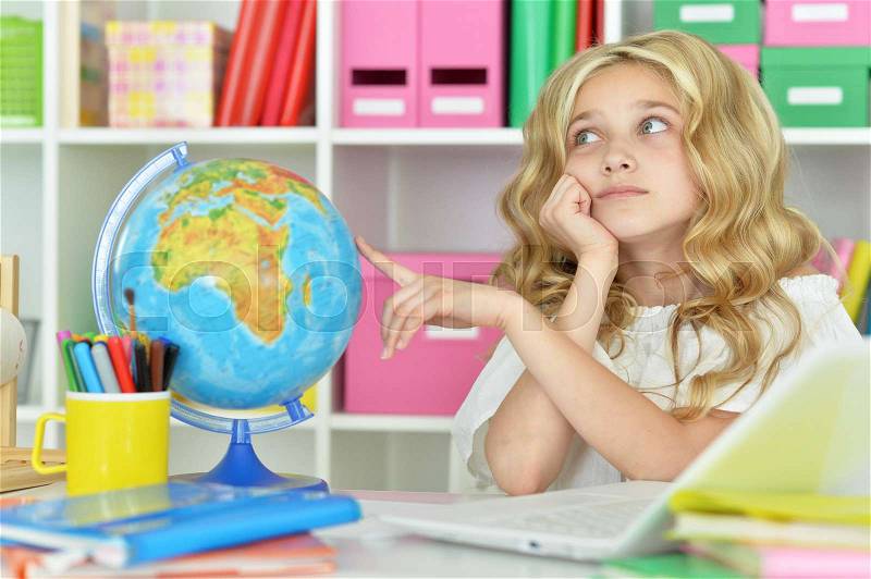 Teen girl siting at table and hugging world globe, stock photo