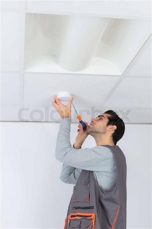 An electrician with a fire detector, stock photo